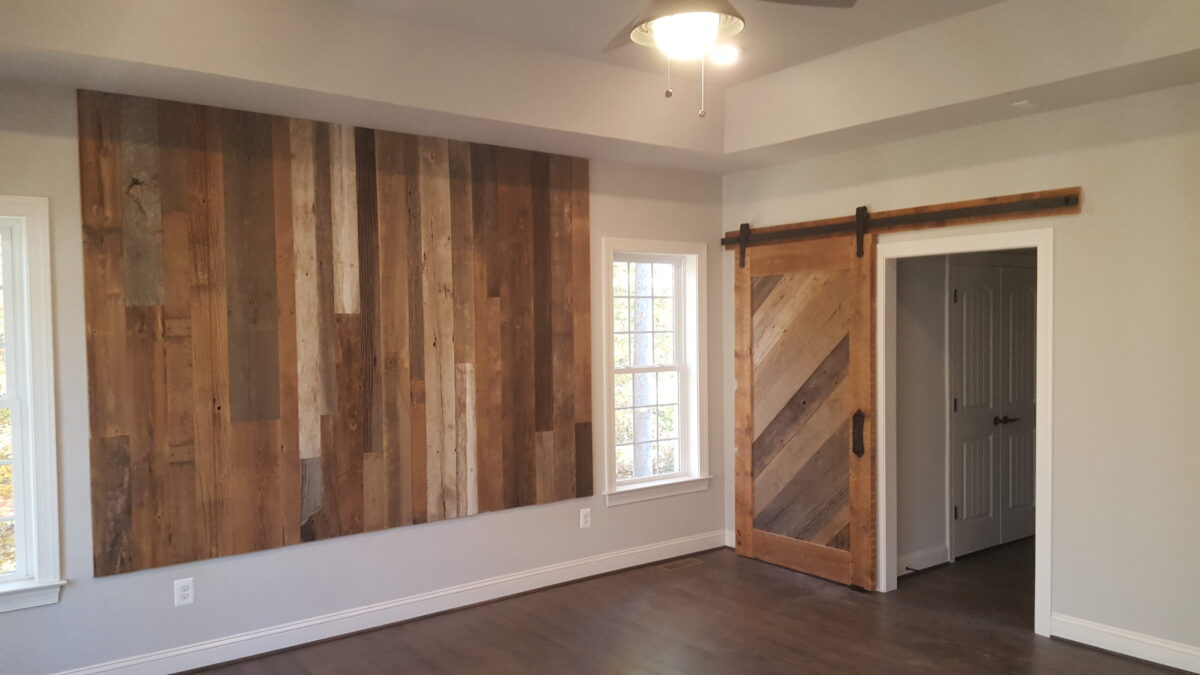 A wall of custom barn siding alongside an interior, sliding barn door representing some of the available architectural materials at Fraser Wood Elements in Fredericksburg, VA.