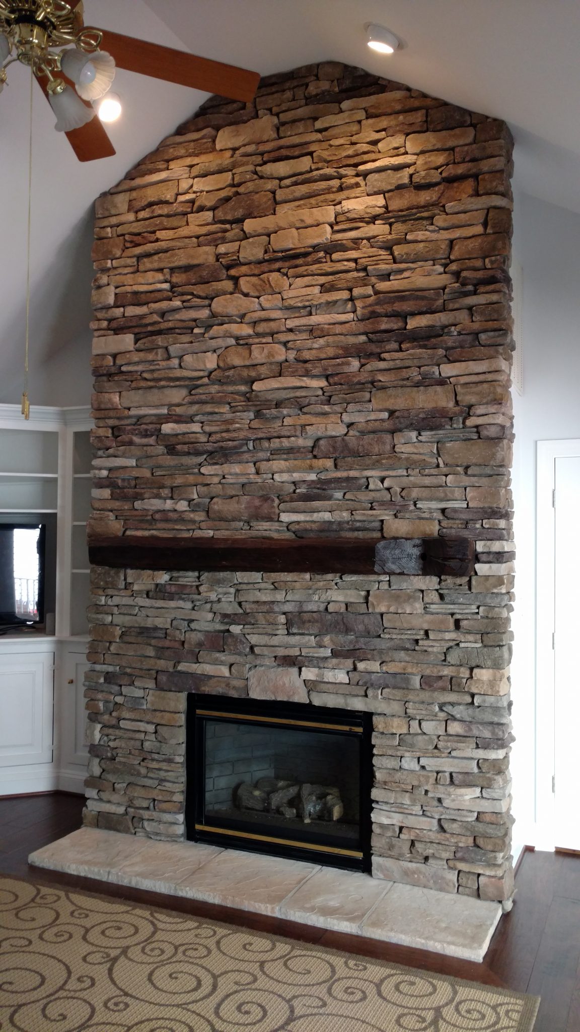 An example of a stone face mantel shelf installed in a living room by Fraser Wood Elements in Fredericksburg, VA.